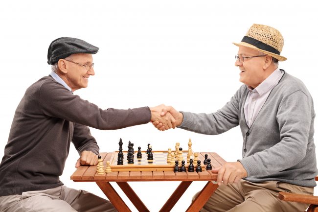 Two seniors shaking hands after a game of chess